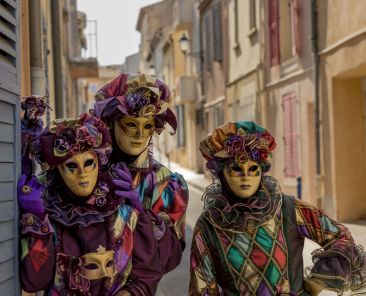 Three people wearing colorful masks and clothes during the carnival
